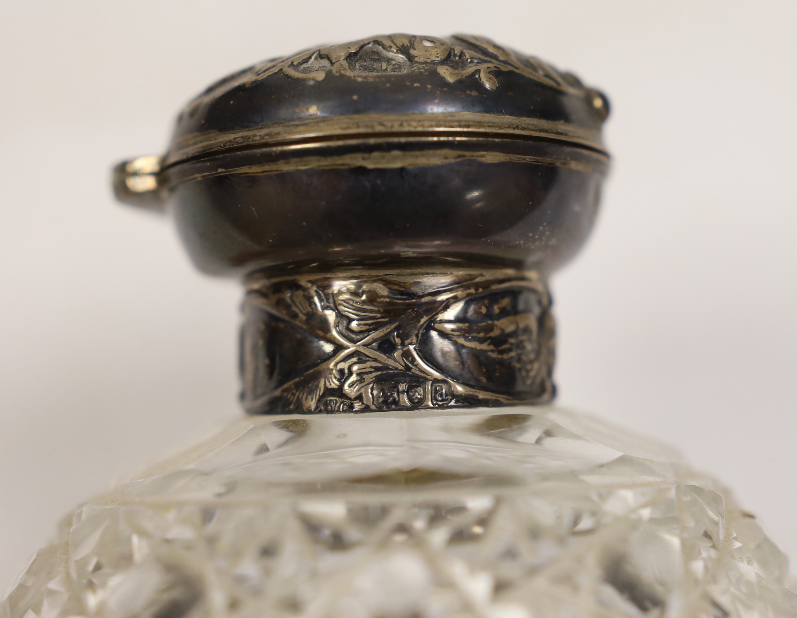 A late Victorian repousse silver mounted cut glass scent bottle, with Reynold's Angels decoration, William Comyns, London, 1896, 13cm.